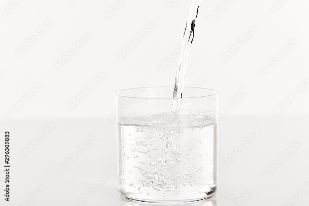 clear fresh water pouring into glass isolated on white clear fresh water pouring into glass isolated on white