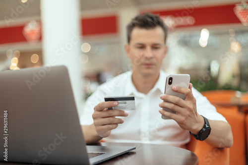 Man using smartphone and laptop computer for online shopping . Credit card photo