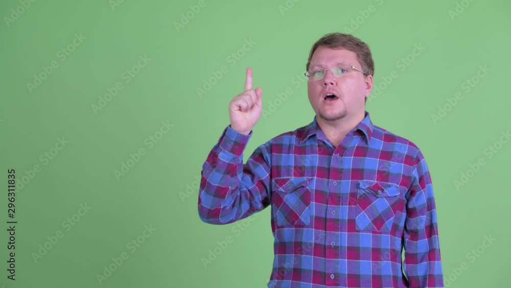 Happy overweight bearded hipster man talking while pointing up Happy overweight bearded hipster man talking while pointing up