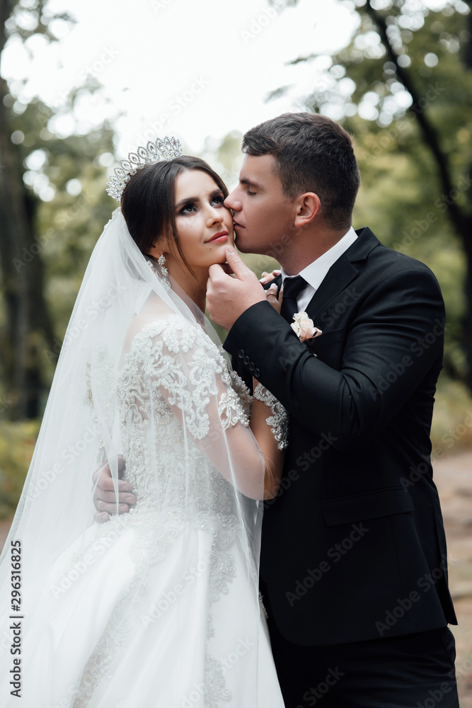Bride and groom in a park kissing. Couple newlyweds bride and groom at a wedding in nature green forest are kissing photo portrait. Loving wedding couple outdoor. Wedding Couple Bride and groom in a park kissing. Couple newlyweds bride and groom at a wedding in nature green forest are kissing photo portrait. Loving wedding couple outdoor. Wedding Couple