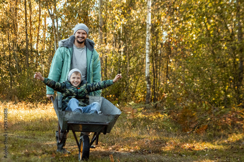 Dad spends time with his son, a happy little boy pushed by a dad. Active outdoor games for children in the fall.