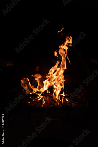 Burning wood at night. Campfire at touristic camp in nature in mountains. Flame and fire sparks on dark abstract background.