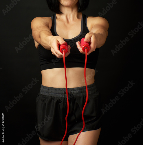 young woman with a sports figure in black uniform holds a red rope for jumping