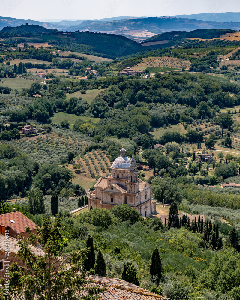 Φωτογραφία A church In Montalcino Tuscany With Trees, Vineyards, Crops And Hills in the Bac