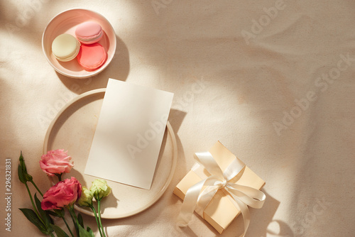 Top view of blank note, kraft envelope, gift box, fabric and flowers over light background