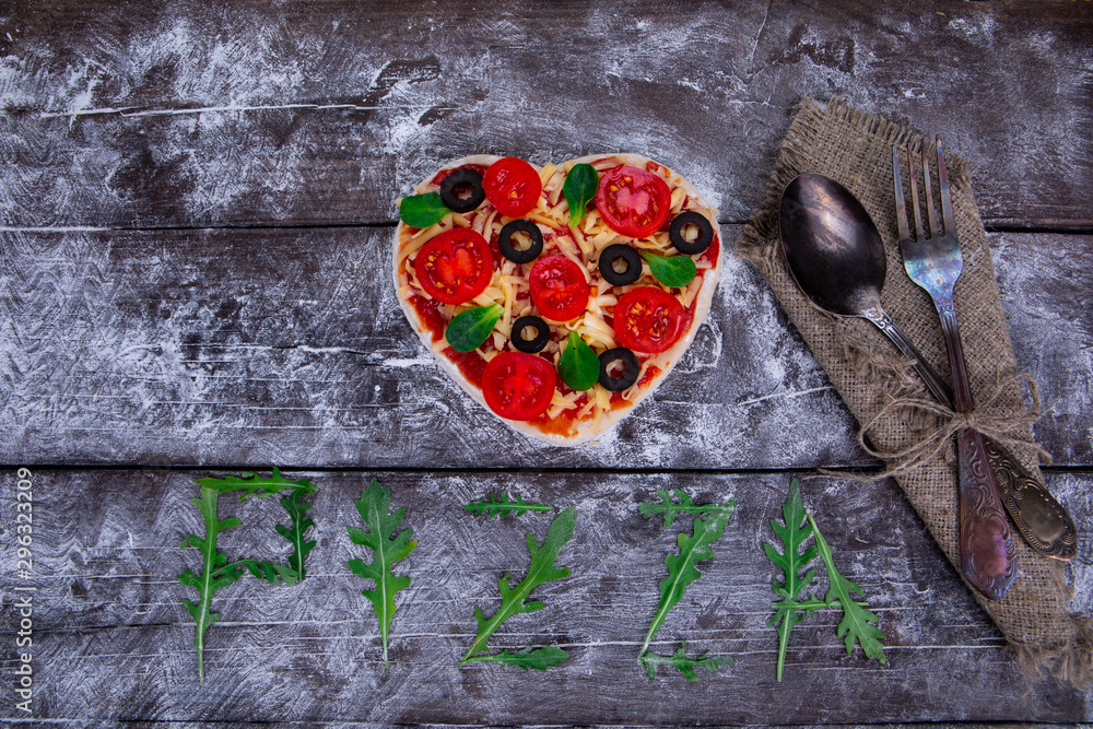 Heart shaped pizza ingredients. The name of the pizza is written in arugula.