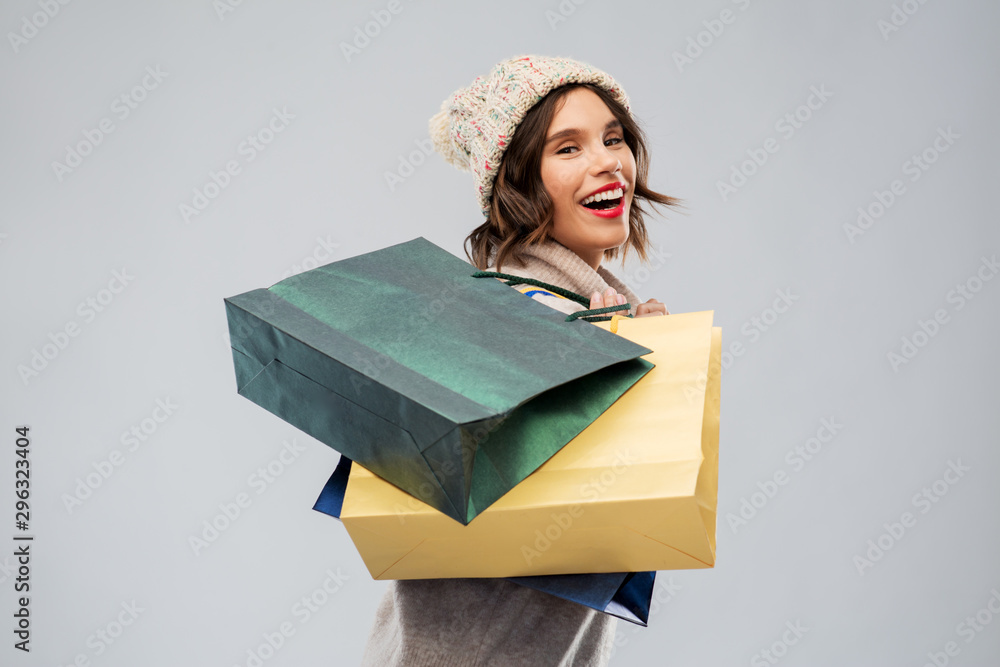 © Syda Productions - christmas, seasonal sale and consumerism concept - happy smiling young woman in knitted winter hat and sweater with shopping bags over grey background © Syda Productions - christmas, seasonal sale and consumerism concept - happy smiling young woman in knitted winter hat and sweater with shopping bags over grey background