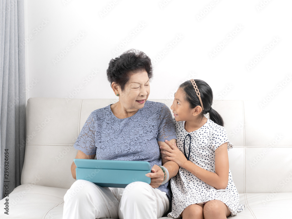 Asian senior woman and girl using tablet at home, lifestyle concept.