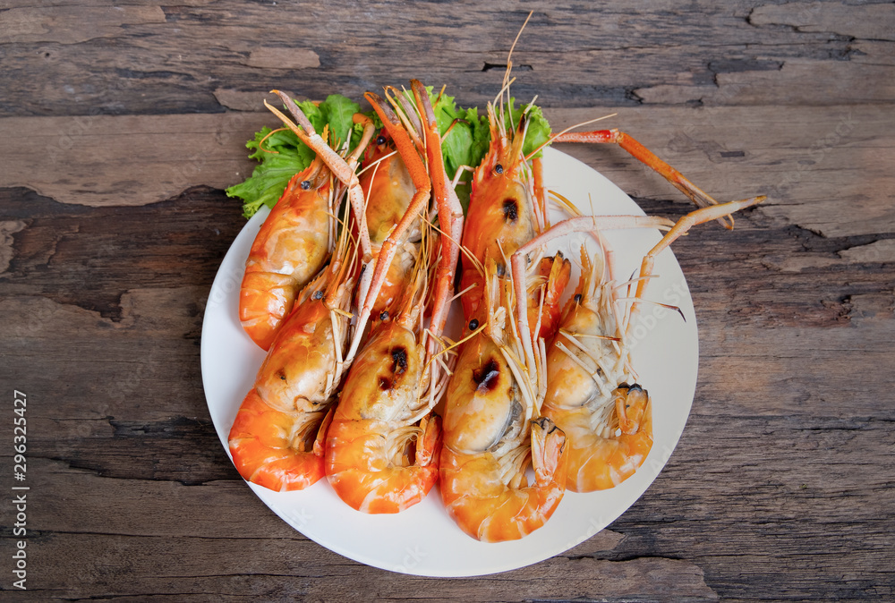Grilled shrimp and seafood sauce is very tasty on a white plate on a wooden background. Grilled shrimp and seafood sauce is very tasty on a white plate on a wooden background.