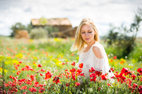 Beautiful young female  in white dress  in poppy field of wild flowers