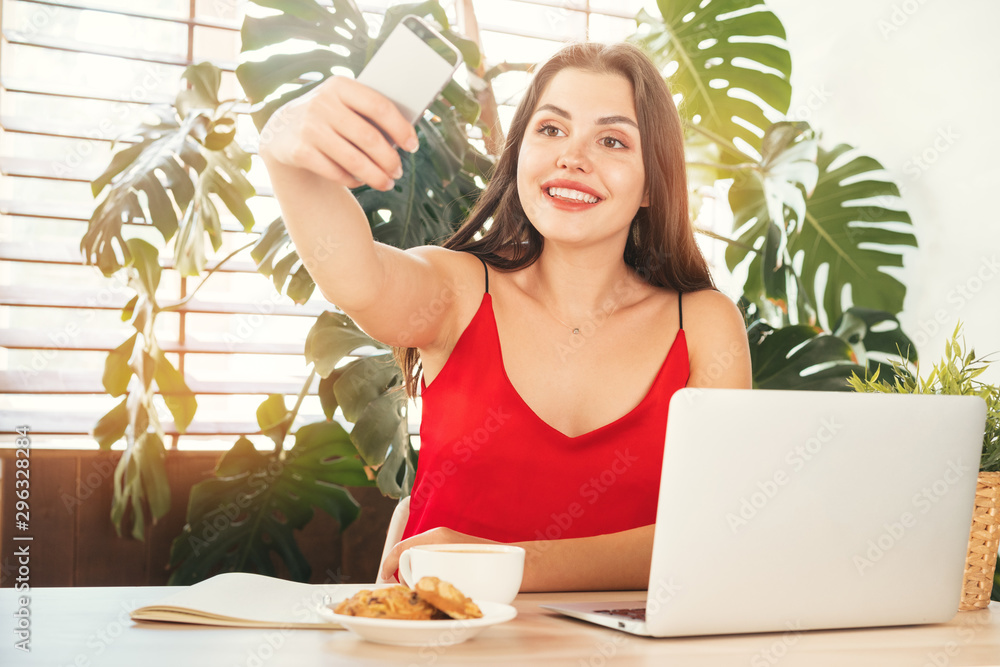 Young smiling student girl doing selfie with her smartphone while at work Young smiling student girl doing selfie with her smartphone while at work