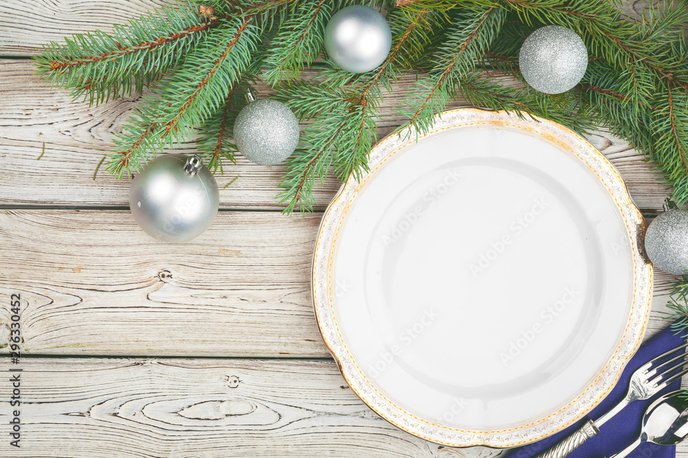 Wooden table with pine tree branches and holiday table setting Wooden table with pine tree branches and holiday table setting