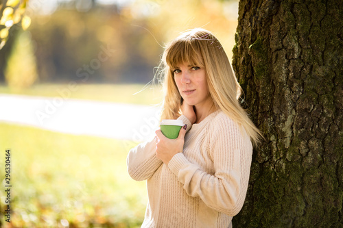 girl sits and relax on the ground in the autumn forest with coffee