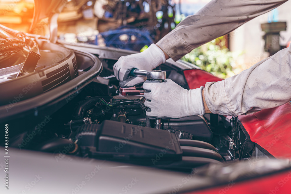 Naklejka premium mechanic Engine check concept. Close up hand doing car service. Tight nut by socket block.