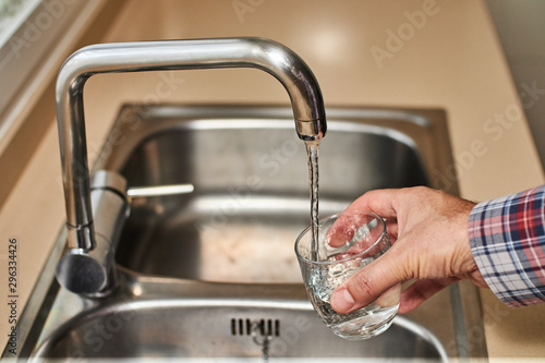 man filling a glass with water in the kitchen