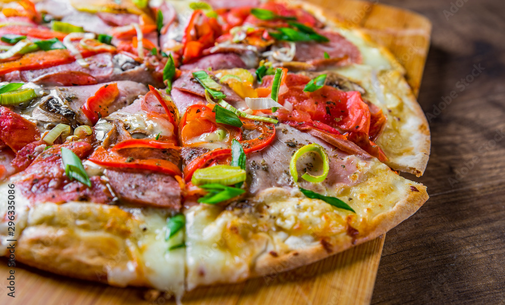 Pizza with Mozzarella cheese, ham, tomato, salami, onion, pepper, Spices. Italian pizza on wooden table background Pizza with Mozzarella cheese, ham, tomato, salami, onion, pepper, Spices. Italian pizza on wooden table background