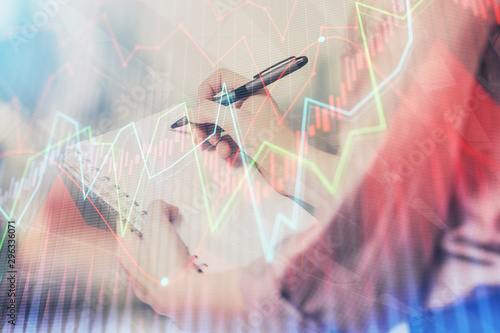 Multi exposure of hands making notes with forex chart huds. Stock market concept.