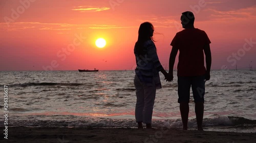 Couple of lovers silhouettes standing at seashore and enjoy sunset, happy foe new beggining
