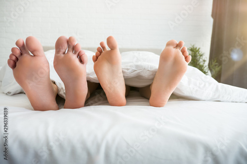 man and woman barefeet lying in the bed