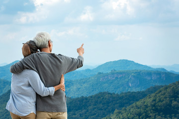 Asian Lifestyle senior couple hug and pointing the mountain nature.  Old people happy in love romantic and relax time.Â  Tourism family elderly retirement travel in summer leisure and destination.