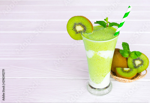 Kiwi yogurt fruit juice smoothie and green kiwi juice drink healthy delicious taste in a glass for weight loss on a white wooden background.