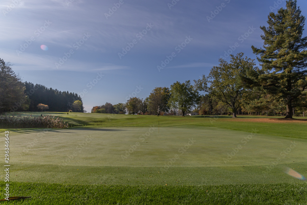 green grass golf course in fall with autumn leaves and trees