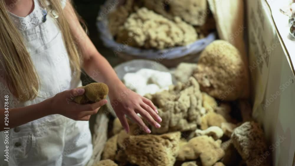 Young girl choosing natural sponge in cosmetics shop. Young girl trying bath sponge in souvenir shop of natural cosmetic Young girl choosing natural sponge in cosmetics shop. Young girl trying bath sponge in souvenir shop of natural cosmetic