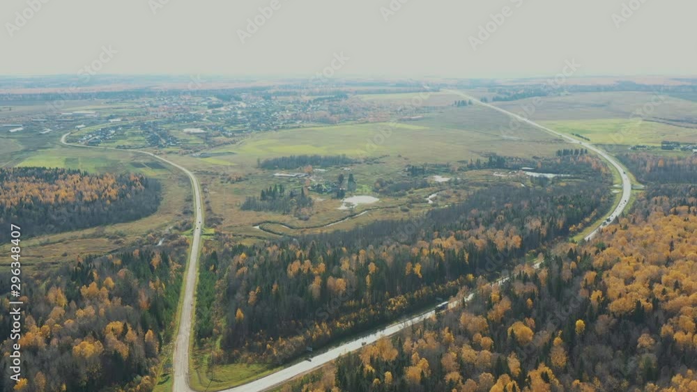 Aerial Flight over the road between fields and autumn trees in yellow, orange, green forest. Autumn colors Aerial Flight over the road between fields and autumn trees in yellow, orange, green forest. Autumn colors