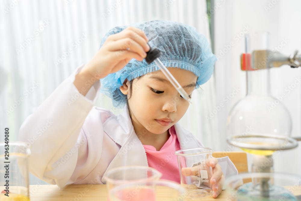 Asian little girl playing with fun as a scientist working in a lab equipped with colored glass tubes. Asian little girl playing with fun as a scientist working in a lab equipped with colored glass tubes.