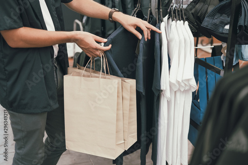 man holding shopping bags choosing clothes at store shop