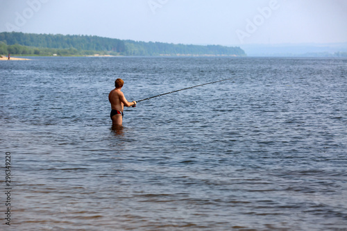 A man is fishing with a fishing rod standing in the water.