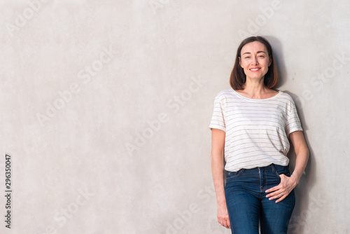 Horizontal attractive older woman smiling by white wall