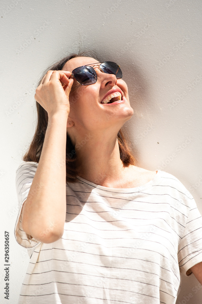 older woman laughing with sunglasses by white background older woman laughing with sunglasses by white background