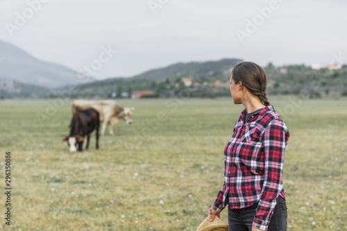 Woman looking at grazing cows in the field