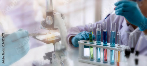 Laboratory concept; Scientist use dropper to transfer chemical reagent to test tube. He observe the chemical reaction in laboratory with blurred background of microscope testing