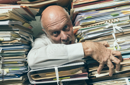 Panicked businessman overloaded with paperwork photo