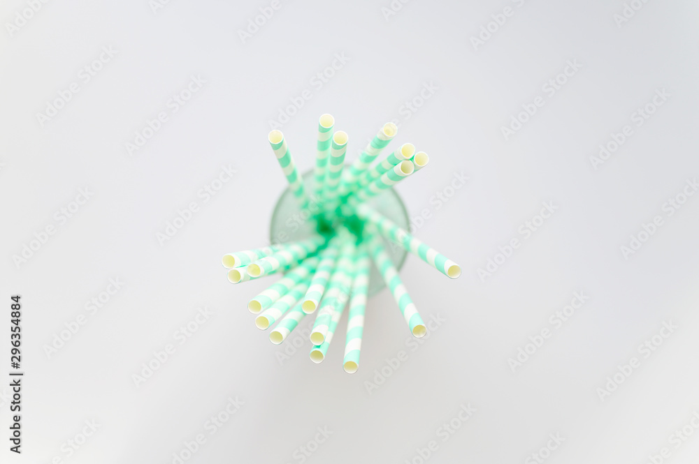 pile of paper striped white and green drinking straws for party in clear glass cup on white background pile of paper striped white and green drinking straws for party in clear glass cup on white background