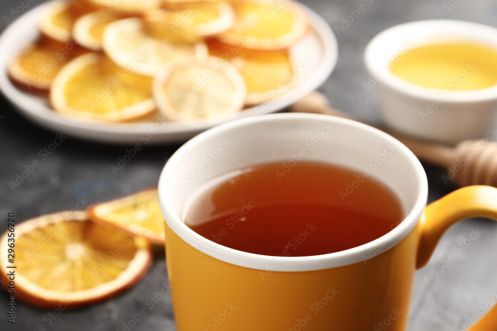 A cup of tea close-up on a dark background with dry citruses and honey. Top view. A cup of tea close-up on a dark background with dry citruses and honey. Top view.