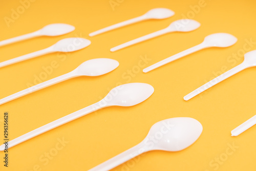 many plastic spoons on yellow background