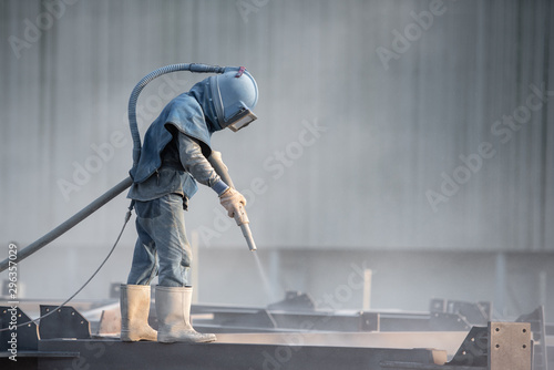 Sand blasting process, Industial worker using sand blasting process preparation cleaning surface on steel before painting in factory workshop.