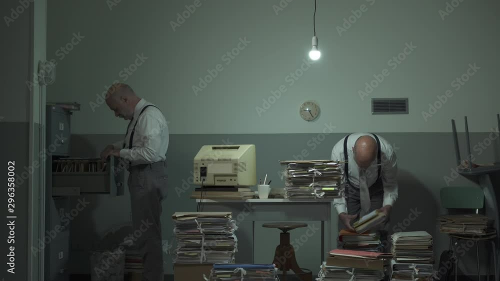 Multitasking office worker searching for files in his office