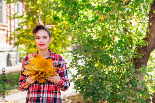 Beautiful woman with make up and hair in pin up holding big bouquet of maple yellow leaves. photo