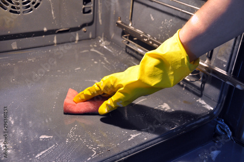 cleaning the oven in the kitchen. hand in a yellow economic glove.