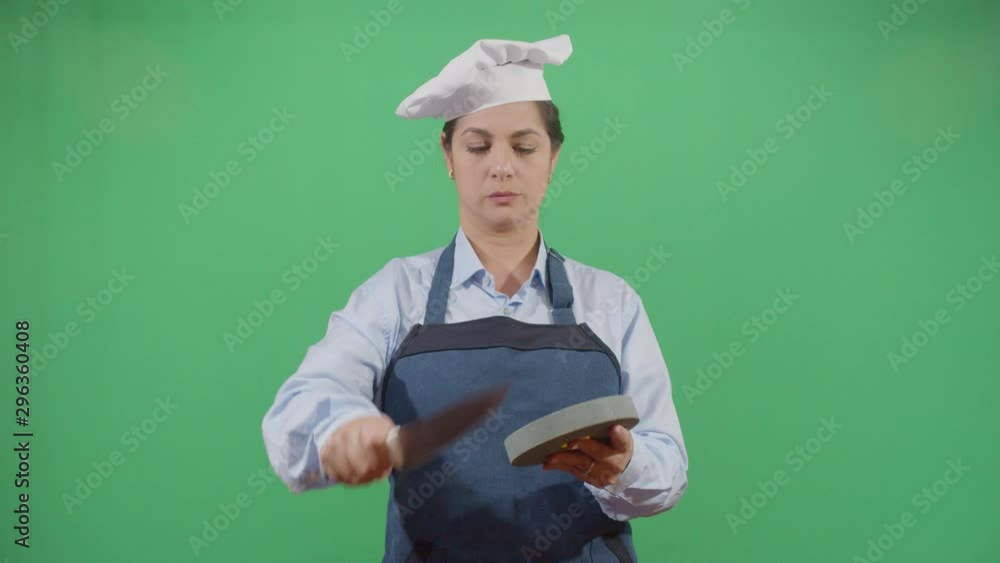 Knife Sharpening By A Funny Woman Cook. Studio Isolated Shot Against Green Screen Background Knife Sharpening By A Funny Woman Cook. Studio Isolated Shot Against Green Screen Background