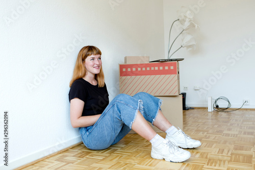 Smiling young student sitting on the floor during move