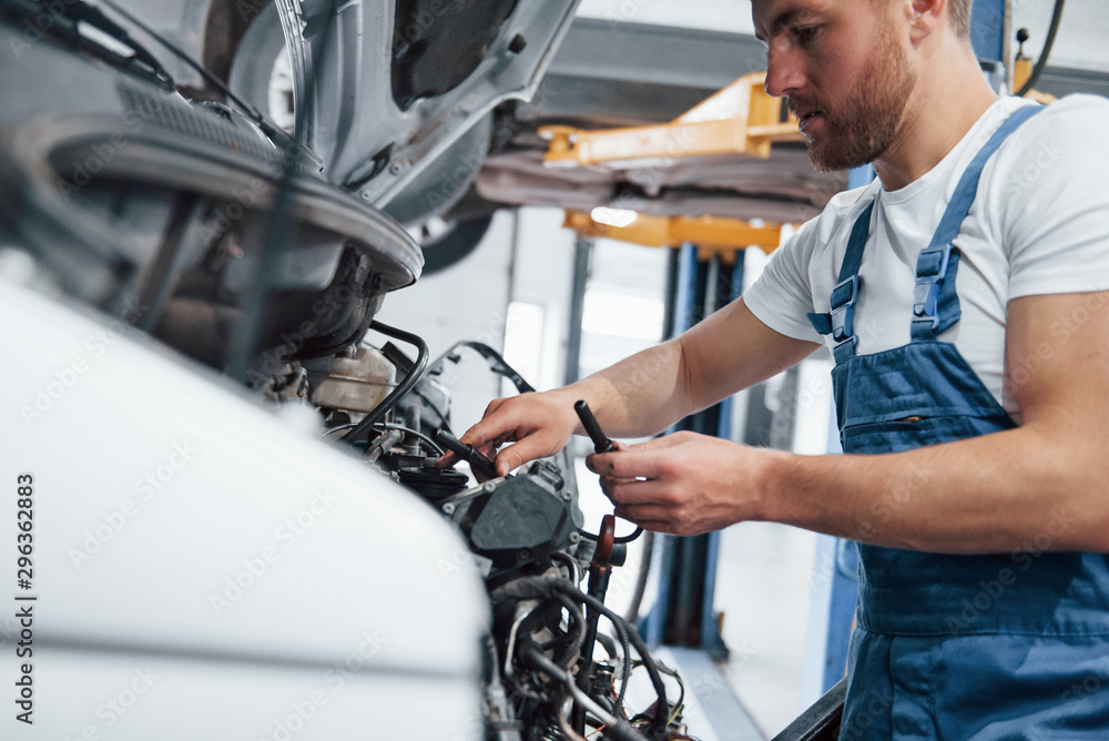 Trust your repairman. Employee in the blue colored uniform works in the automobile salon Trust your repairman. Employee in the blue colored uniform works in the automobile salon