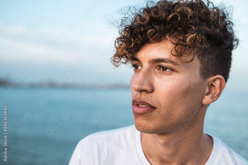 Portrait of young man with curly hair by the sea Portrait of young man with curly hair by the sea