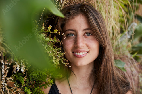 Portrait of smiling young woman in front of plant wall photo