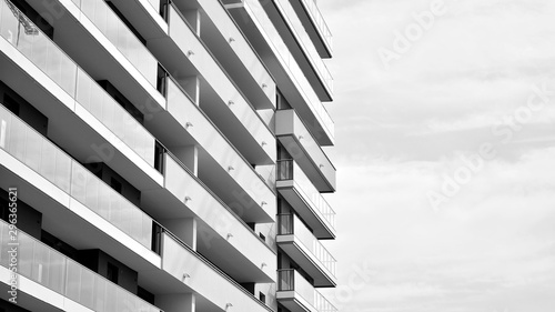 Fototapeta Naklejka Na Ścianę i Meble -   Fragment of a facade of a building with windows and balconies. Modern home with many flats. Black and white.
