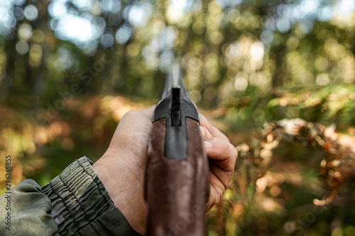 Finger on the trigger of a hunting rifle in the autumn forest close-up. The hunting period, the fall season is open, the search for prey.